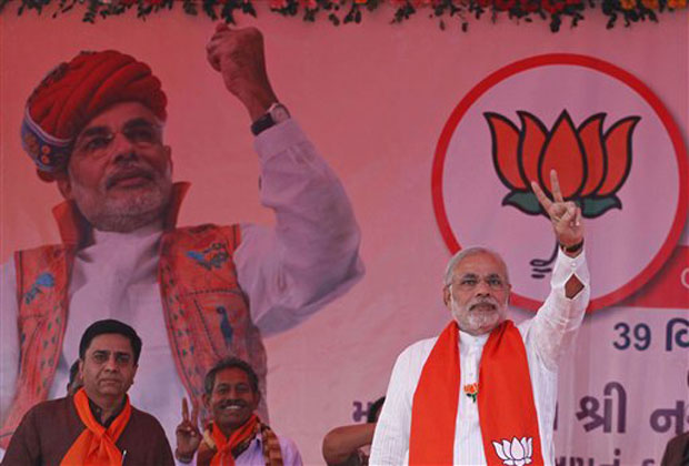 In this Monday, Dec. 3, 2012 photo, Gujarat Chief Minister Narendra Modi, right, flashes a victory sign during an election campaign at Viramgam, Gujarat, India.