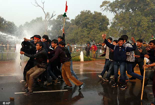Protesters try to shield themselves from water canon discharge during a violent demonstration near the India Gate against a gang rape and brutal beating of a 23-year-old student on a bus last week, in New Delhi, India, Sunday, Dec. 23, 2012. The attack last Sunday has sparked days of protests across the country. (AP Photo/ Saurabh Das)