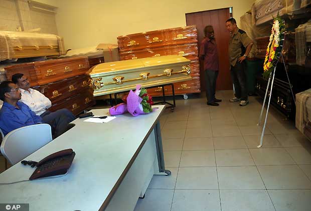 Workers from a Hindu Casket service and officials from the Indian High Commission wait in front of the empty coffin, center, for the body of a young Indian woman who was gang-raped in Delhi on Saturday Dec. 29, 2012 in Singapore. (AP Photo/Wong Maye-E)