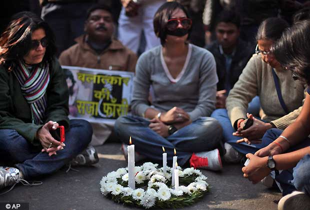 A wreath and candles are placed on a road as Indians sit around it while attending a gathering to mourn the death of a 23-year-old gang rape victim in New Delhi, India, Saturday, Dec. 29, 2012. (AP Photo/Altaf Qadri)