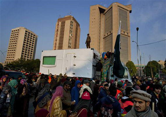 Supporters of Pakistani Sunni Muslim cleric Tahir-ul-Qadri walk alongside a vehicle carrying ul-Qadri at an anti government rally in Islamabad, Pakistan, Tuesday, Jan. 15, 2013.(AP Photo)