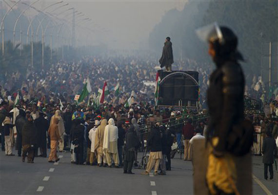 A Pakistani police officer stands guard on a shipping container while supporters of Pakistan Sunni Muslim cleric Tahir-ul-Qadri participate in an anti government rally in Islamabad, Pakistan on Tuesday, Jan. 15, 2013.(AP Photo)