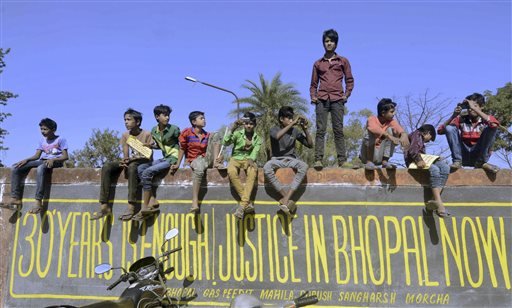 Children sit on the wall of the abundant Union Carbide factory as they watch a rally on the 30th anniversary of the Bhopal gas tragedy