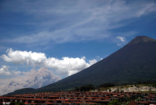 Volcanic ash spews from the Volcan de Fuego or Volcano of Fire, left, as seen from Palin, south of Guatemala City, Thursday, Sept. 13, 2012. The long simmering volcano exploded into a series of powerful eruptions Thursday, hurling thick clouds of ash nearly two miles (three kilometers) high, spewing rivers of lava down its flanks. (AP Photo)