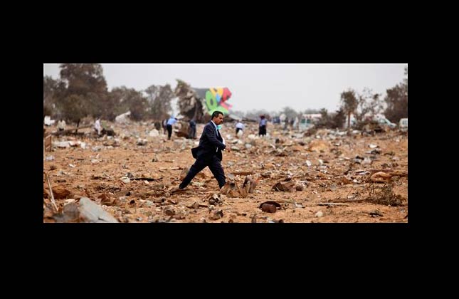 An unidentified man walks through the wreckage as rescue teams search the site of the Libyan Afriqiyah Airways plane crash in Tripoli, Libya, Wednesday, May 12, 2010. A Libyan Afriqiyah Airways plane with 104 people on board crashed on landing Wednesday at the airport in the Libyan capital Tripoli and a search and rescue operation was under way, the airlines said. (AP Photo/Abdel Meguid al Fergany)