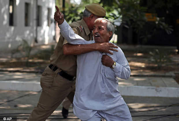 An Indian policeman tries to restrain a lone anti corruption protester outside Prime Minister Manmohan Singh's residence in New Delhi, India, Friday, Oct. 12, 2012. Singh has been criticized for presiding meekly over a corrupt government. (AP Photo)