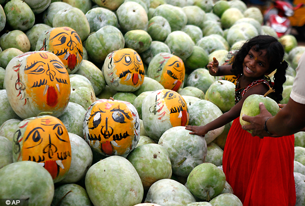 A child reacts as she buys pumpkins to be painted with demon faces during the Durga Puja festival in Chennai, Sunday, Oct. 21, 2012. Devotees believe that smashing pumpkins painted with demon faces drive away evil spirits. (AP Photo)