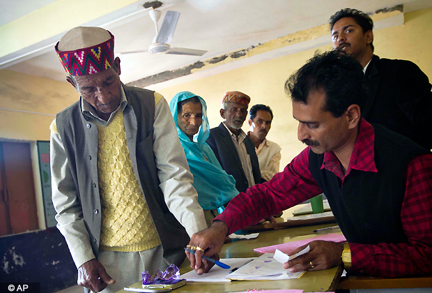 An elderly person in a traditional Himachali cap is helped by an official to put his thumb impression before casting his vote for the Himachal Pradesh state assembly elections in Dharmsala, Nov. 4, 2012. Counting of votes will take place on Dec. 20. (AP Photo)