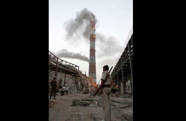 A security worker watches a rescue operation at the site of an under construction chimney that collapsed in Jhansi, India, Tuesday, May 25, 2010. The 220 meter (721 feet) high chimney being constructed by a Central agency at Parichcha thermal power station collapsed and several laborers are believed to be trapped in the debris, according to a news agency. (AP Photo/Rajesh Kumar Singh)