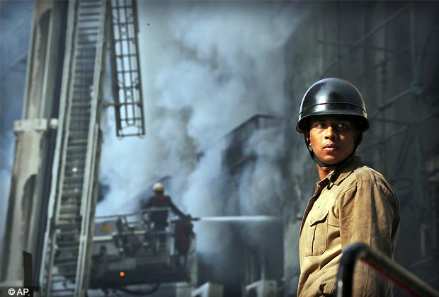 A firefighter waits for water as others, background, battle a large fire in the Himalaya House office tower in Connaught Place in New Delhi, Nov. 19, 2012. One person died in the fire. (AP Photo)