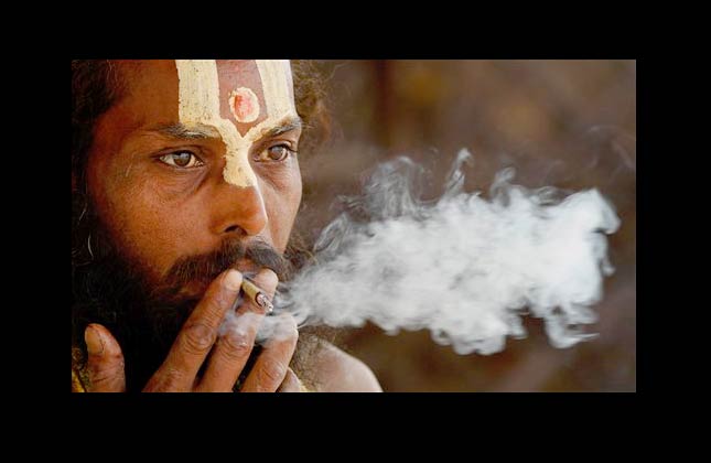 A Hindu holy man smokes bidi, or a small hand rolled Indian cigarette, in Allahabad, India, Monday, May 31, 2010. Bidis are popular among poor Indians because they are cheaper. A packet containing 10 bidis costs about 2 rupees (4 cents). (AP Photo/Rajesh Kumar Singh)