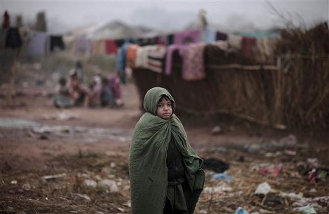 A Pakistani boy wraps himself with a sheet to shield from the cold, while walking in a slum, on a foggy morning in Islamabad, Pakistan, Monday, Jan. 7, 2013. (AP Photo/Muhammed Muheisen)