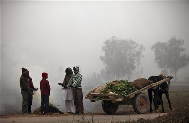 Indian vendors warm themselves near a fire on a cold and foggy morning in Jammu, India, Tuesday, Jan. 8, 2013. North India continues to face below average weather conditions with dense fog affecting flights and trains. More than 100 people have died of exposure as northern India deals with historically cold temperatures. (AP Photo/Channi Anand)