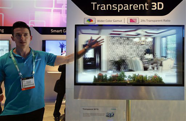 Payton Tyrell, left, demonstrates on a transparent 3D TV at the Hisense booth at the International Consumer Electronics Show in Las Vegas, Tuesday, Jan. 8, 2013. (AP Photo/Jae C. Hong)