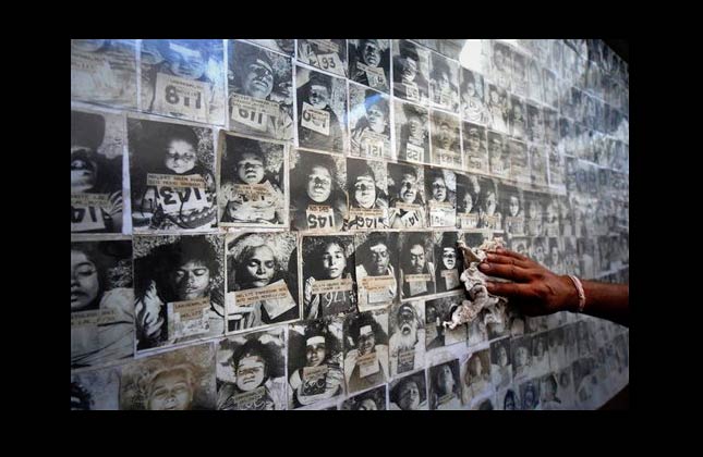 A worker cleans the dust as he displays a panel of photographs of people who died in the 1984 Bhopal gas disaster at the forensic department of Gandhi Medical college in Bhopal, India, Tuesday, June 8, 2010. A court Monday convicted seven former senior employees of Union Carbide's Indian subsidiary of death by negligence for their roles in the 1984 leak of toxic gas that killed an estimated 15,000 people in the world's worst industrial disaster. (AP Photo/Prakash Hatvalne)