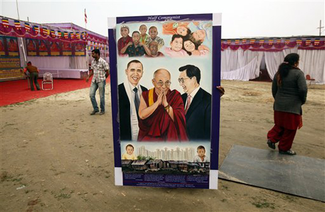 An Indian worker carries a portrait of Tibetan spiritual leader the Dalai Lama in preparation of his Sunday visit at Sangam, the confluence of rivers Ganges, Yamuna and mythical Saraswati, during Mahakumbh festival in Allahabad, india, Saturday, Feb. 2, 2013. Millions of Hindu pilgrims are expected to attend the Maha Kumbh festival, which is one of the world's largest religious gatherings that lasts 55 days and falls every 12 years. (AP Photo/ Rajesh Kumar Singh)