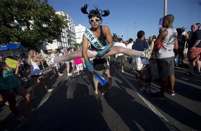 A reveler performs a split jump at the Simpatia e Quase Amor or Kindness is almost love, block party, a pre Carnival celebrations in Rio de Janeiro, Brazil, Saturday, Feb. 2, 2013. According to Rio's tourism office, Rio's street Carnival this year will consist of 492 block parties, attended by an estimated five million Carnival enthusiasts. (AP Photo/Silvia Izquierdo)