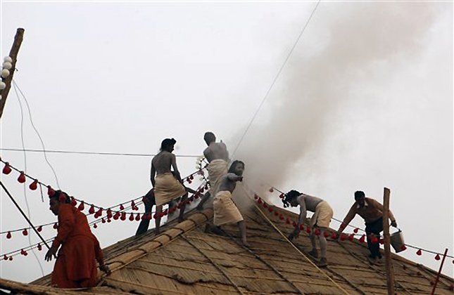 Hindu monks extinguish the fire on the roof of a temporary temple structure of the Hindu sect Sri Panchayati Bada Udasin Akhara at Sangam, the confluence of rivers Ganges, Yamuna during the Mahakumbh festival in Allahabad, India, Sunday, Feb. 3, 2013. There was no casualty or major damages. Millions of Hindu pilgrims are expected to attend the Maha Kumbh festival, which is one of the world's largest religious gatherings that lasts 55 days and falls every 12 years. (AP Photo/ Rajesh Kumar Singh)