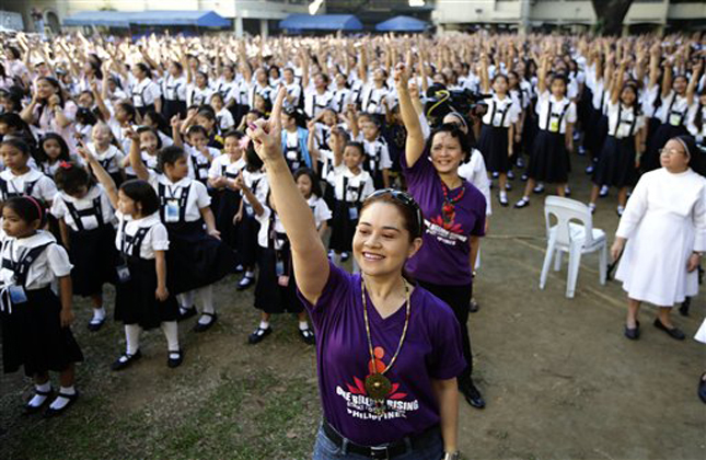 Filipino theater artist Monique Wilson flashes the No.1 sign with students from St. Scholastica's College, an all girls' school, as they dance at their campus in a global kickoff campaign dubbed One Billion Rising, to end violence against women and children on Valentine's Day Thursday Feb. 14, 2013 in Manila, Philippines. Thousands of women and children in various cities in the country danced in the streets, in malls and other places to express support for the One Billion Rising Campaign which also counts Australia and New Zealand as the first countries to rise for the campaign. (AP Photo/Bullit Marquez)