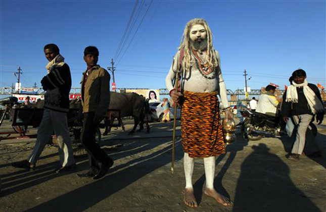 Hindu devotees walk past a Naga sadhu or naked Hindu holy man at Sangam, the confluence of the Rivers Ganges, Yamuna and mythical Saraswati, during the Maha Kumbh festival in Allahabad, India , Thursday, Feb. 7, 2013. Millions of Hindu pilgrims are attending the Maha Kumbh festival, which is one of the world's largest religious gatherings that lasts 55 days and falls every 12 years. During the festival pilgrims bathe in the holy Ganges River in a ritual they believe can wash away their sins.(AP Photo /Rajesh Kumar Singh)