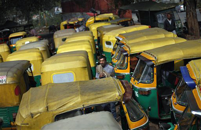 An Indian auto rickshaw driver stands among dozens of auto rickshaws parked during a nationwide strike called by trade unions in New Delhi, India, Wednesday, Feb. 20, 2013. Sporadic violence has broken out in India at the beginning of a two day strike by labor unions protesting rising prices and government policies to open the economy. Millions of bank and factory workers stayed away from work and public transport was shut down Wednesday after India's major trade unions called the countrywide strike. (AP Photo/Altaf Qadri)