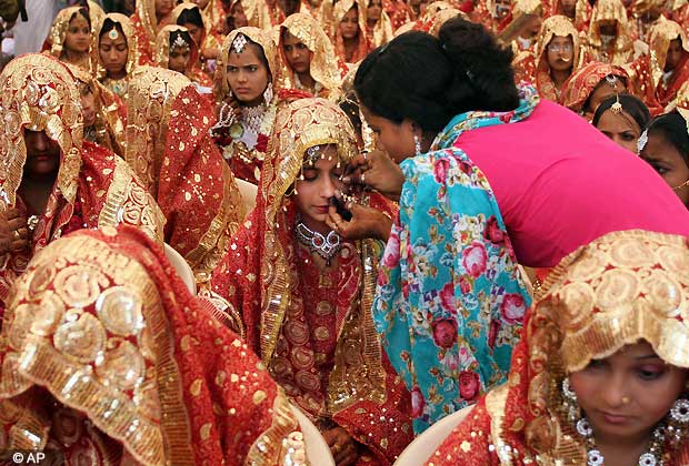 An Indian relative helps a bride get ready before a ritual during the Muslim community mass marriage in Ahmadabad, India, Friday, Feb. 22, 2013.