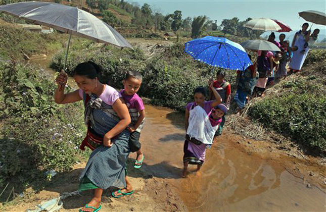 Khasi women carry their babies and walk towards a polling station to cast their votes in Marngar, in the northeastern Indian state of Meghalaya, Saturday, Feb. 23, 2013. Elections for the state legislatures in the northeastern Indian states of Meghalaya and Nagaland are being held Saturday. (AP Photo/Anupam Nath)