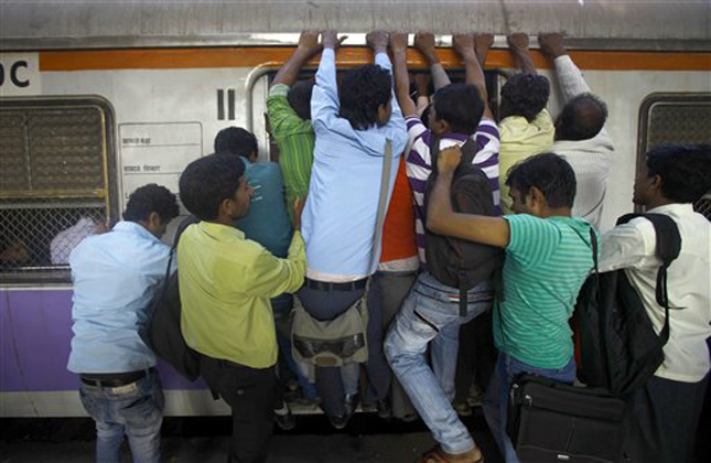 Indian commuters try to board an overcrowded train in Mumbai, India, Tuesday, Feb. 26, 2013. Indian Railway Minister Pawan Kumar Bansal is presenting the country's rail budget for next fiscal year in the parliament Tuesday, Feb. 26, 2013. Indian railway network is one of the world's largest, with some 14 million passengers daily and some 64,000 kilometers (40,000 miles) of railway track cut through some of the most densely populated cities.(AP Photo/Rafiq Maqbool)