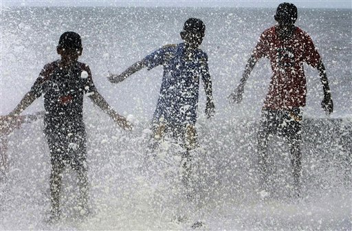 Children play in a wave hitting the shore during high tide in the Arabian Sea at the Worli promenade in Mumbai, India, Sunday, June 13, 2010. (AP Photo/Rajanish Kakade)