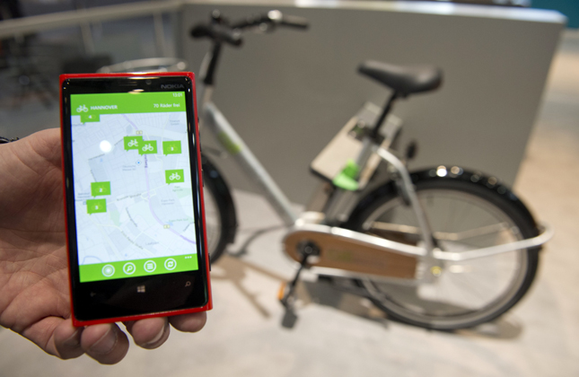 An employee showcases a Windows Phone 8 by HTC, with an app that helps to find and rent out rental bikes, at the Microsoft booth ahead of the CeBIT 2013 at the fairground in Hanover, Lower Saxony, Germany, on Sunday 03 February 2013. The CeBIT 2013 will cover the issue of Shareconomy from 5 to 9 March 2013. (Photo dapd/IANS)