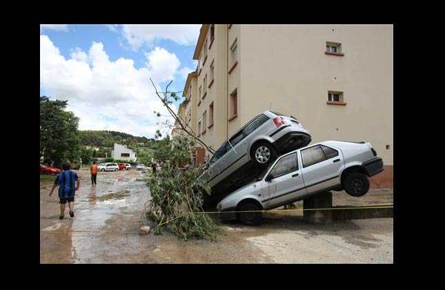 Residents walk past piled cars, in Trans en Provence, southern France, Wednesday, June 16, 2010 after floods. Regional authorities in southeastern France say more than a dozen people have been killed and many are missing in the aftermath of flash floods that followed powerful rainstorms. Unusually heavy rains recently in the Var region have transformed streets into muddy rivers that swept up trees, cars and other objects. (AP Photo/Claude Paris)
