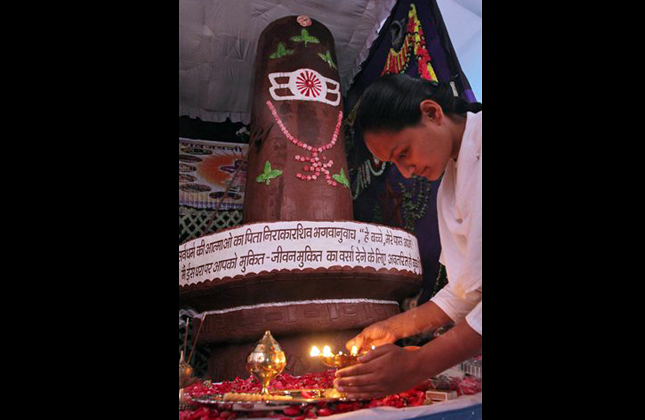 An Indian spiritual woman lights a lamp during the inauguration of a 17 feet high Shivling, an idol symbolic of Hindu God Shiva, made from 505 kilogram of chocolate ahead of Mahashivratri festival in Ahmadabad, India, Friday, March 8, 2013. Hindus across the world will celebrate Mahashivratri or Shiva's night festival on March 10. (AP Photo/Ajit Solanki)