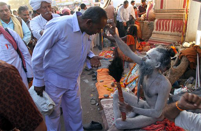 An Indian naked Hindu holy man applies ash on the forehead of a devotee during the Maha Shivratri fair in Junagadh, in the western Indian state of Gujarat, Saturday, March 9, 2013. The five day long fair will conclude on Sunday, coinciding with Shivratri, the festival dedicated to the worship of Hindu God Shiva. (AP Photo/Ajit Solanki)