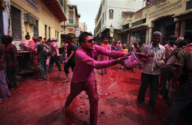 An Indian teases passes by by pretending to throw colored water on them during Holi celebrations outside Banke Bihari temple in Vrindavan, India, Wednesday, March 27, 2013. Holi, the Hindu festival of colors that also marks the advent of spring, is being celebrated across the country Wednesday. (AP Photo/Altaf Qadri)