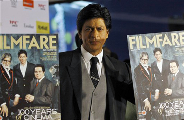 In this Wednesday, April 10, 2013 photo, Bollywood star Shahrukh Khan poses for photographers with copies of the Filmfare magazine after unveiling it to celebrate 100 years of Indian cinema, at an event in Mumbai, India. (AP Photo/Rafiq Maqbool)