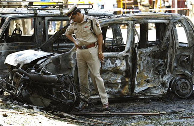 A police officer inspects the site of an explosion at a residential neighborhood near the office of India's main opposition Bharatiya Janata Party in Bangalore, India, Wednesday, April 17, 2013. A powerful bomb exploded Wednesday near the office of the political party in the southern Indian city of Bangalore, injuring at least 16 people, police said. (AP Photo/Aijaz Rahi)
