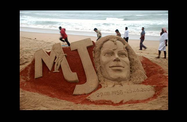 People walk past a sand sculpture of US performer Michael Jackson created to mark the first anniversary of his death, at the Bay of Bengal coast, in Puri, Orissa state, India, Thursday, June 24, 2010. (AP Photo)