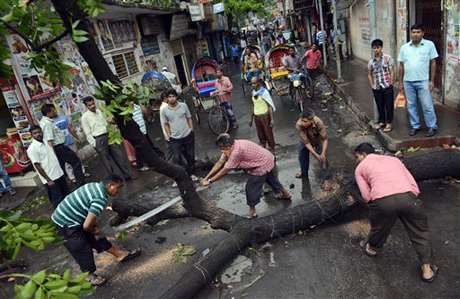 Bangladeshi workers cut a tree left by protesters to block a road during a protest in Savar near Dhaka, Bangladesh, Monday, May 6, 2013. At least 15 people died in clashes in Bangladesh Monday between police and Islamic hardliners demanding that Bangladesh implement an anti blasphemy law, police said. (AP Photo/Ismail Ferdous)