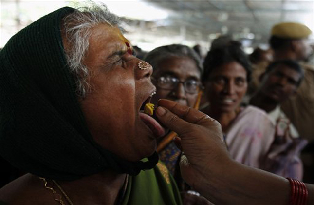 A member of the Goud family administers fish medicine to an asthma patient in Hyderabad, India, Saturday, June 8, 2013. Started by the Bathini Goud family, the therapy is a secret formula of herbs, handed down by generations only to family members. The herbs are inserted in the mouth of a live sardine, or murrel fish, and slipped into a patient's throat. (AP Photo/Mahesh Kumar A.)
