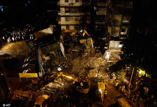 Rescue workers look for trapped people after a residential building collapsed in Mahim, central Mumbai, India, Monday, June 10, 2013. One woman was killed and around four people were injured when a portion of a four storey building caved in, apparently due to heavy rain in Mumbai on Monday, a municipal officer said.
