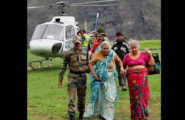 In this Wednesday June 19, 2013 photo, an Indian army soldier helps flood affected elderly pilgrims after being evacuated from upper reaches of mountains, in Chamoli, in Indian northern state of Uttrakhand. Days after floods killed more than 100 people rescuers used helicopters and climbed through mountain paths to reach nearly 4,000 people trapped by landslides in a narrow valley near a Hindu shrine in the northern Himalayas, officials said Thursday. (AP Photo)