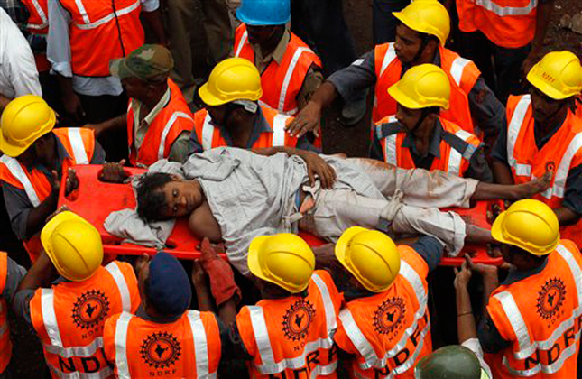 National Disaster Response Force (NDRF) workers carry an injured man rescued from the debris of a building that collapsed on the outskirts of Mumbai, India, T