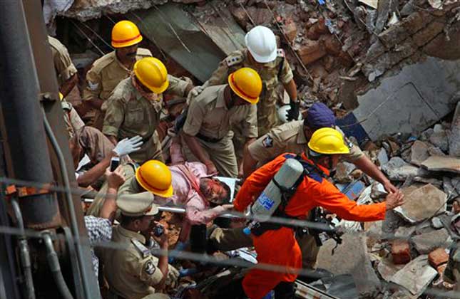 An Indian Fire official rescue an injured from a collapsed building, in Hyderabad, India, Monday, July 8, 2013. An official said at least ten people have been killed and 12 others injured after a two story hotel collapsed in southern India. AP Photo