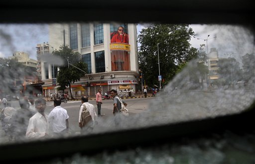 People look at the broken glass of a bus which was broken by protesters during a nationwide strike against the hike in fuel prices near Shiv Sena party headquarters, background, in Mumbai , India, Monday, July 5, 2010. Transportation ground to a halt and businesses were closed Monday in many parts of India following a one day strike by the main opposition parties to protest a government imposed hike in fuel prices.(AP Photo/Rafiq Maqbool)