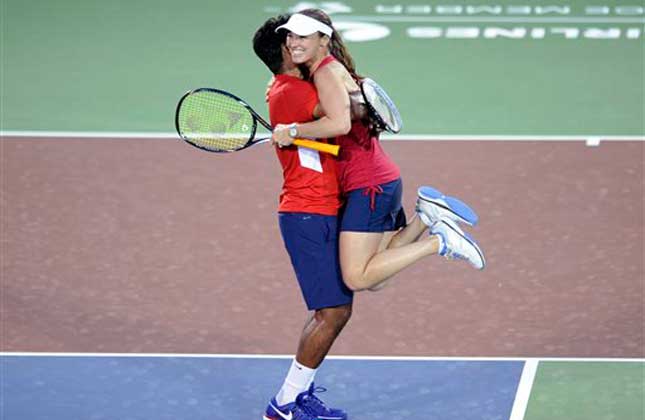 Washington Kastles' Leander Paes, left, of India, picks up and celebrates with Martina Hingis, right, of Switzerland, after they won a World Team Tennis mixed doubles match against the Boston Lobsters, Tuesday, July 9, 2013, in Washington. AP Photo