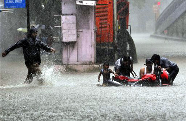 Indian people help retrieve a bike stuck in a water logged street during heavy monsoon rain shower in Mumbai, India, Friday, July 12, 2013. Heavy rains lashed the city Friday impacting vehicular movement due to water logging, according to local reports. AP Photo