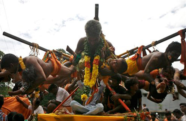 Hindu devotees carry their babies as they hang using hooks pierced through their back from poles that are rotated as part of a ritual during Aadi' celebrations in Chennai, India, Sunday, July 28, 2013. Aadi' is considered a holy month by Tamils and is observed with prayers and offerings to Hindu goddess Durga. (AP Photo)