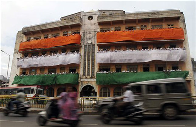 Indian commuters ride past a school building where colors of the Indian flag are displayed on the eve of Independence Day in Ahmadabad, India, Wednesday, Aug. 14, 2013. India commemorates its Independence in 1947 from British colonial rule, on August 15. (AP Photo)