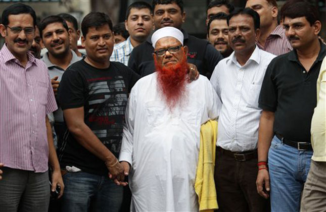 Indian policemen in plain clothes surround Syed Abdul Karim alias Tunda, center in white cap, prior to him being escorted to court, in New Delhi, India, Saturday, Aug. 17, 2013. (AP Photo )