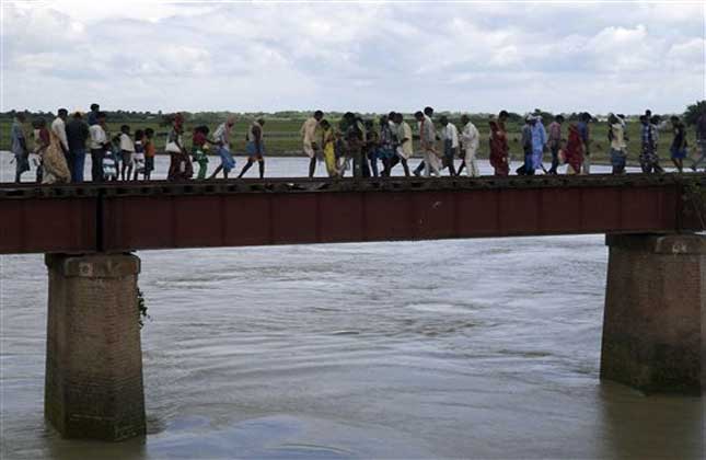 Indian villagers walk through a railway bridge after a train ran over a group of Hindu pilgrims at a crowded station in Dhamara Ghat, Bihar state, India, Monday, Aug. 19, 2013. (AP Photo)